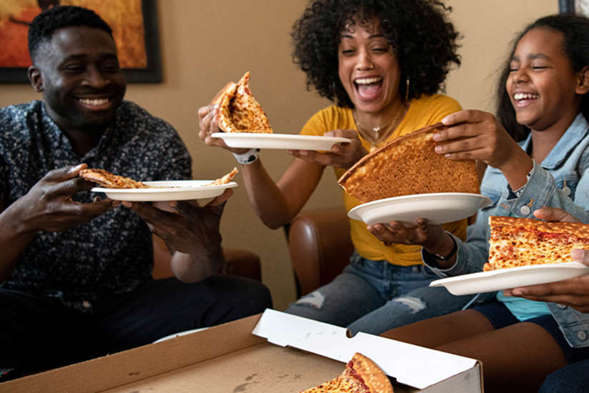 a family enjoying a pizza in their room