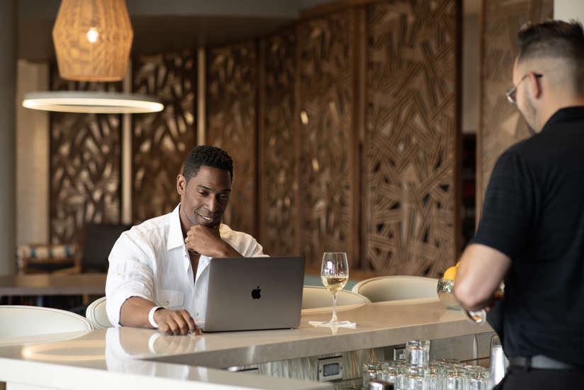 man working on his computer at the bar
