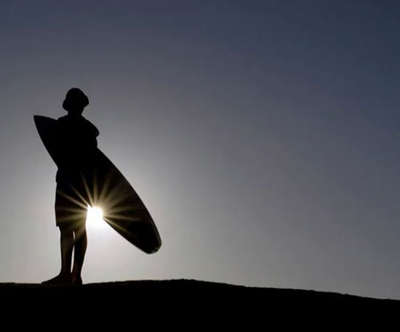 silhouette of a surfer with a hat on