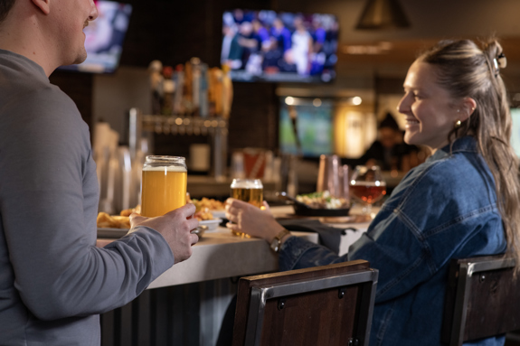 Two people laughing and enjoying draft beer at the bar