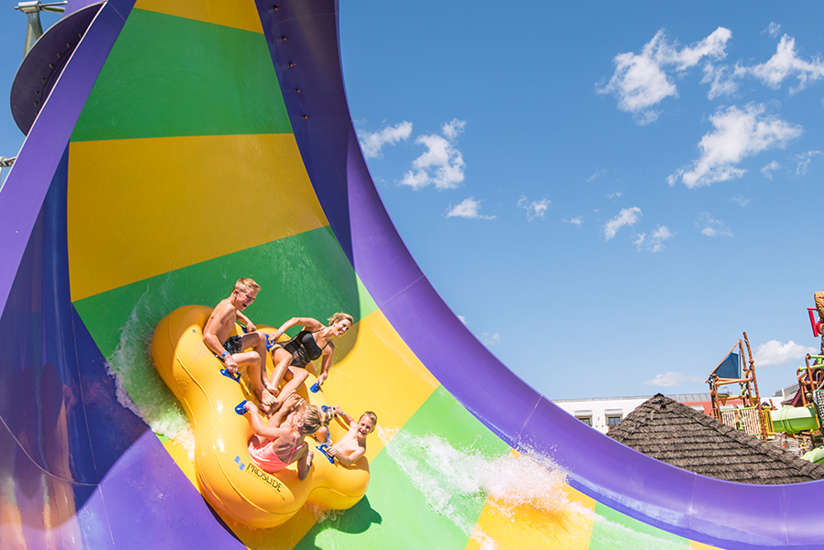 a family sliding down a green, yellow, and purple side outside