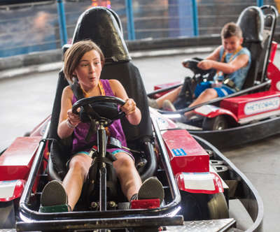 A girl and boy having fun racing around the Meteorace go cart track.