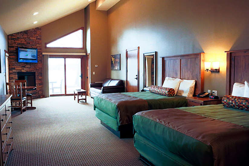 cabin room with two queen size beds, a leather couch, a fireplace, and television set