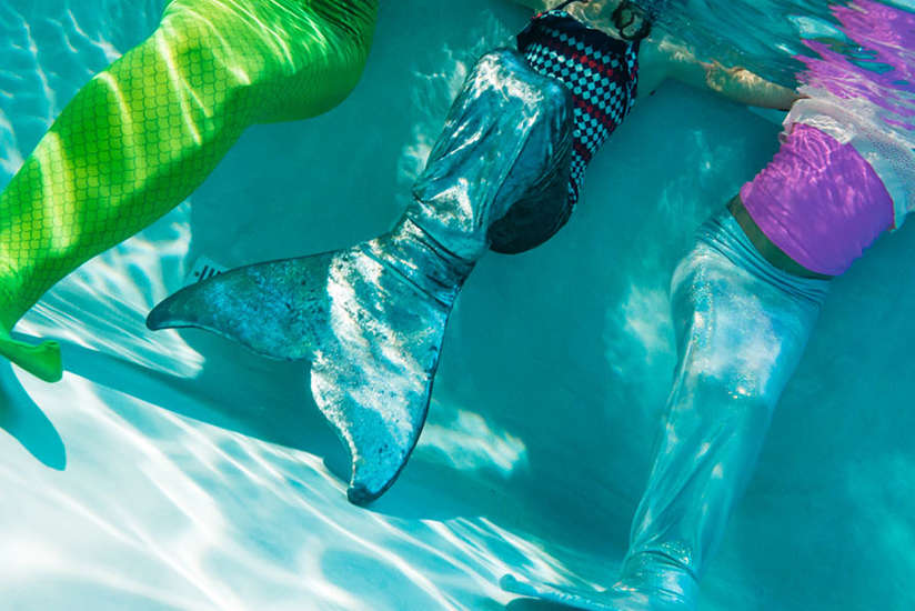 some girls with mermaid tails under wanter