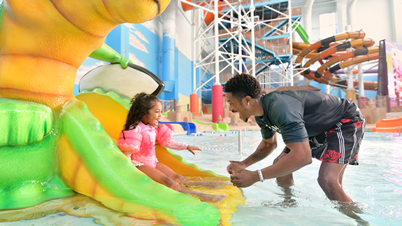 Father and Daughter playing in Coral Cover in the Alligator slide in the Indoor Waterpark