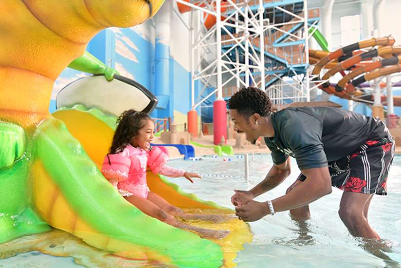 Father and Daughter playing in Coral Cover in the Alligator slide in the Indoor Waterpark