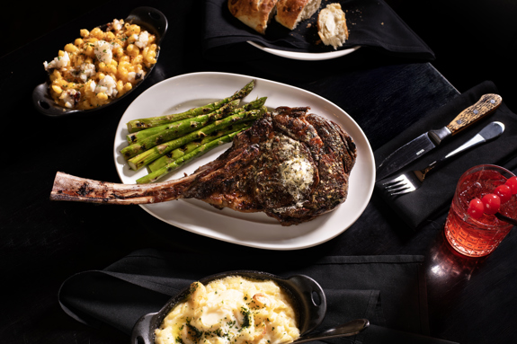 Bone-in-ribeye with delicious sides and a cocktail