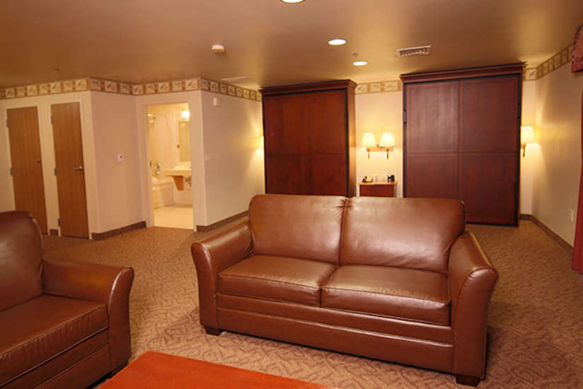 hospitality suite living room with a leather couch and chair and two Murphy beds in the background