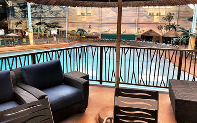 an overview of the wave view cabana. It includes a tv, chairs, couch, and tables. Located right next to the wave pool.