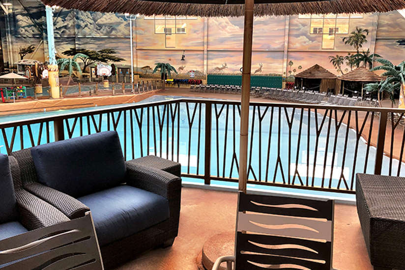 an overview of the wave view cabana. It includes a tv, chairs, couch, and tables. Located right next to the wave pool.