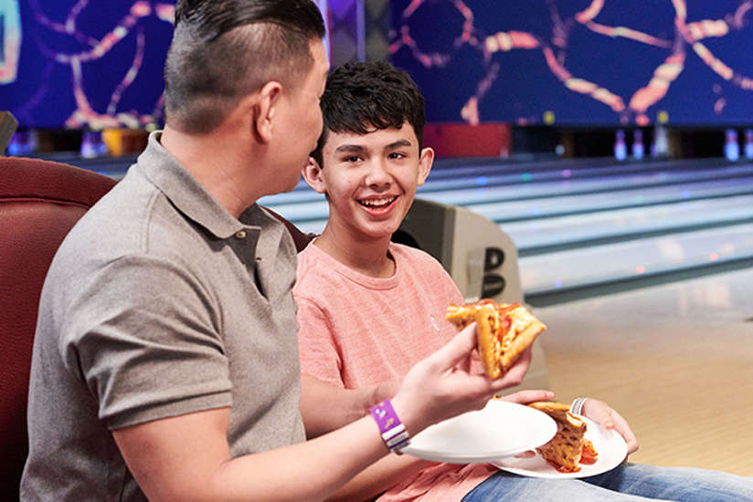 dad and son enjoying some pizza at the volcano lounge and lanes