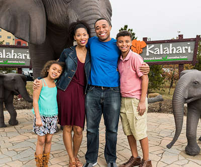 happy family taking a picture outside Kalahari in front of some elephant statues
