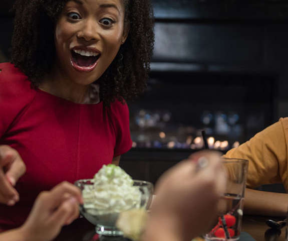 A happy mother watches with a smile as her two children enjoy their dessert