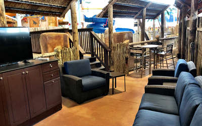 an overview of the madagascar cabana. It includes a tv, chairs, couch, and tables.