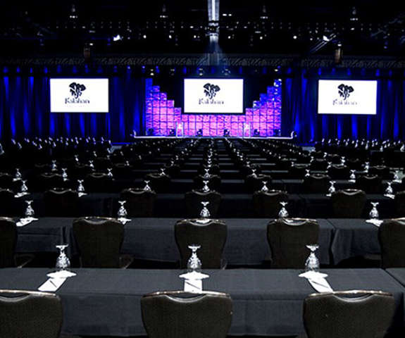 Inside Kalahari's convention center, three large screens display over the stage with rows of tables set for an event