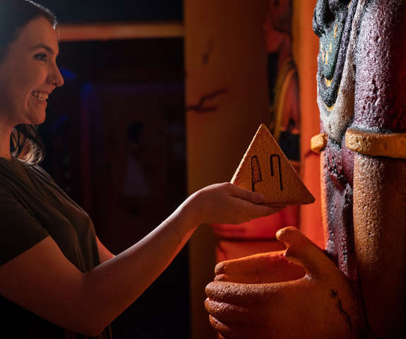 A young lady interacting with an object in the Wrath of Anubis Escape Room.