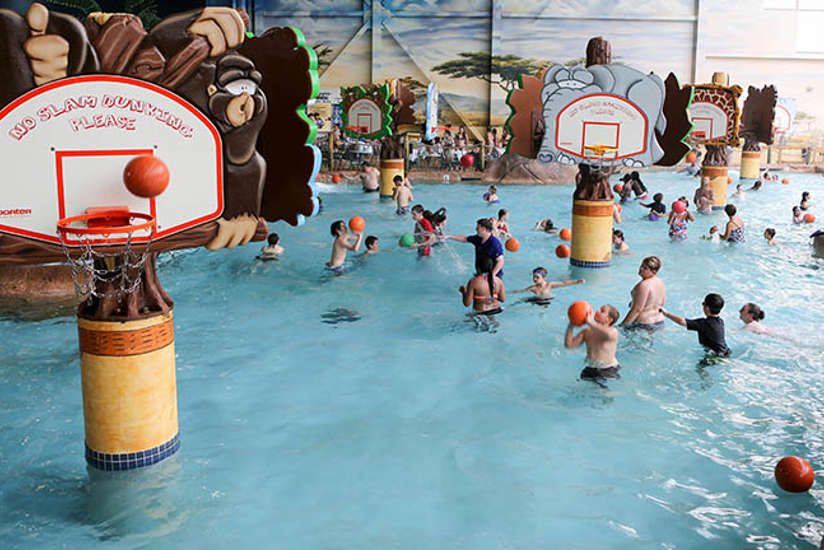 A bunch of kids playing shooting hoops in the pool