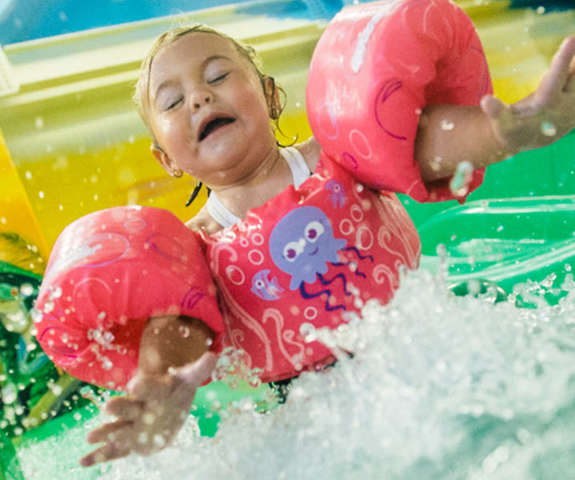 little girl going down slide with eyes closed