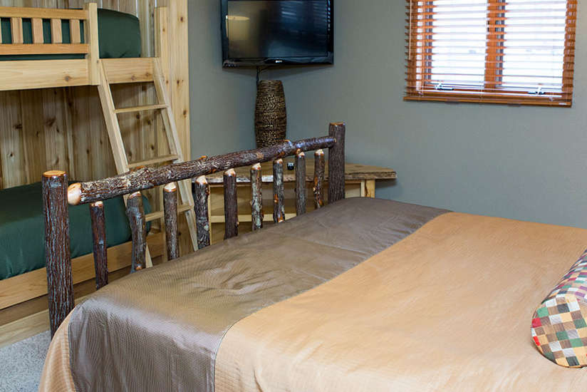 Bedroom with one regular bed and a bunkbed in the Homestead cabin at Lake Delton Waterfront Villas