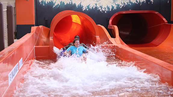 some friends sliding down the kenya korkscrew slide in the indoor waterpark