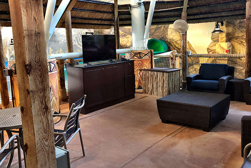 Overview of the Riverview cabana. Includes table, chairs, tv, and a couch. It's by the lazy river.