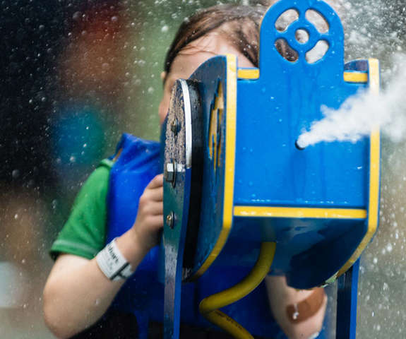 little boy shooting water out of a play toy