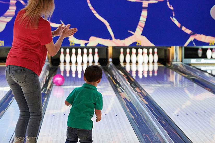 little boy bowling with his mom