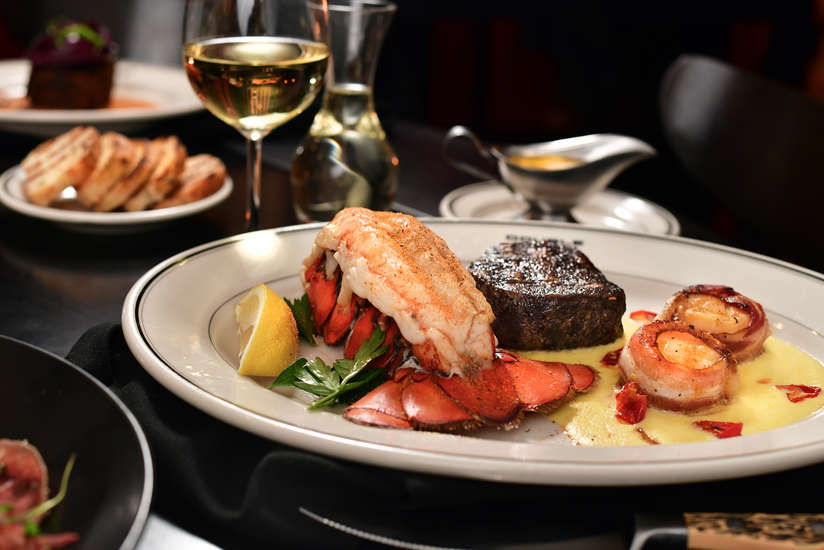 A plate of food containing lobster, steak, and shrimp.