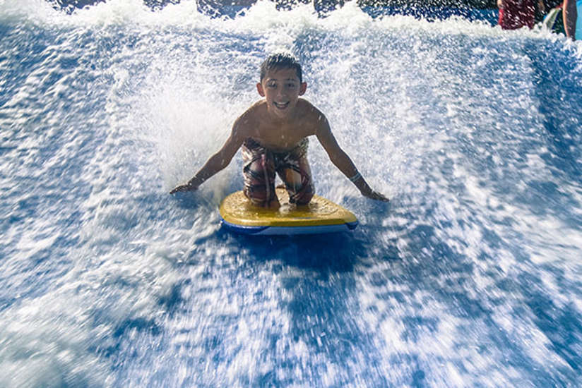 a young boy riding the wave simulator