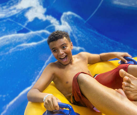 A boy sliding in a tube with a very excited look on his face.