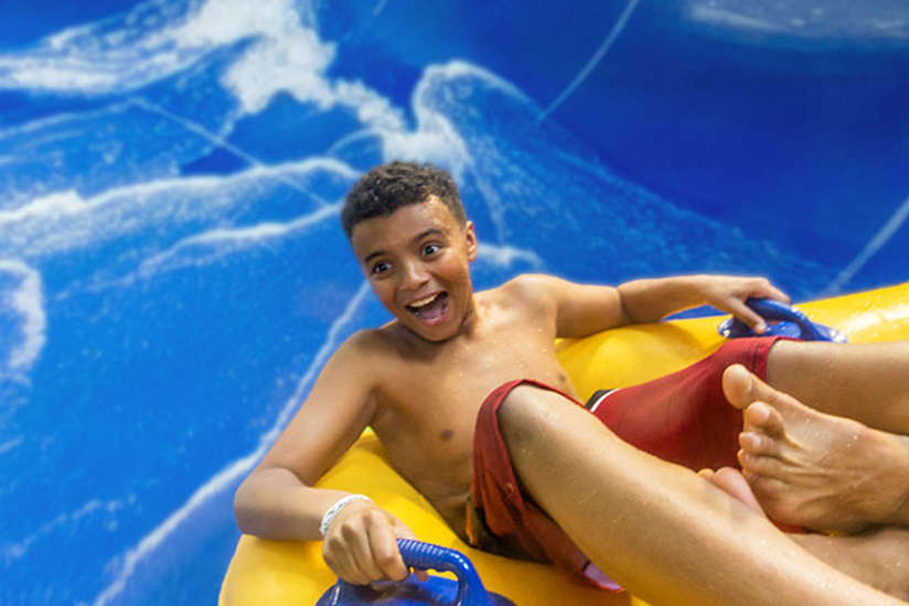 A boy sliding in a tube with a very excited look on his face.