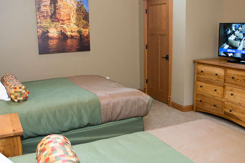 an overview of the Cottage's bedroom with two beds, dresser, and tv