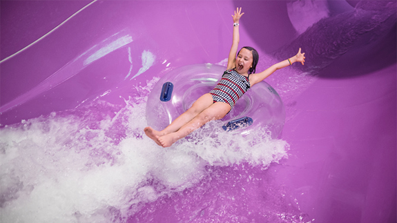A little girl excited going down water slide.