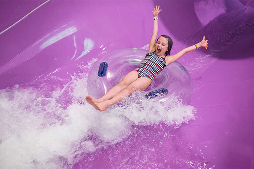A little girl excited going down water slide.