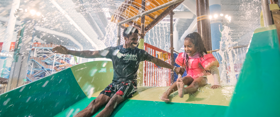 Father and Daughter going down the slide together in the waterpark