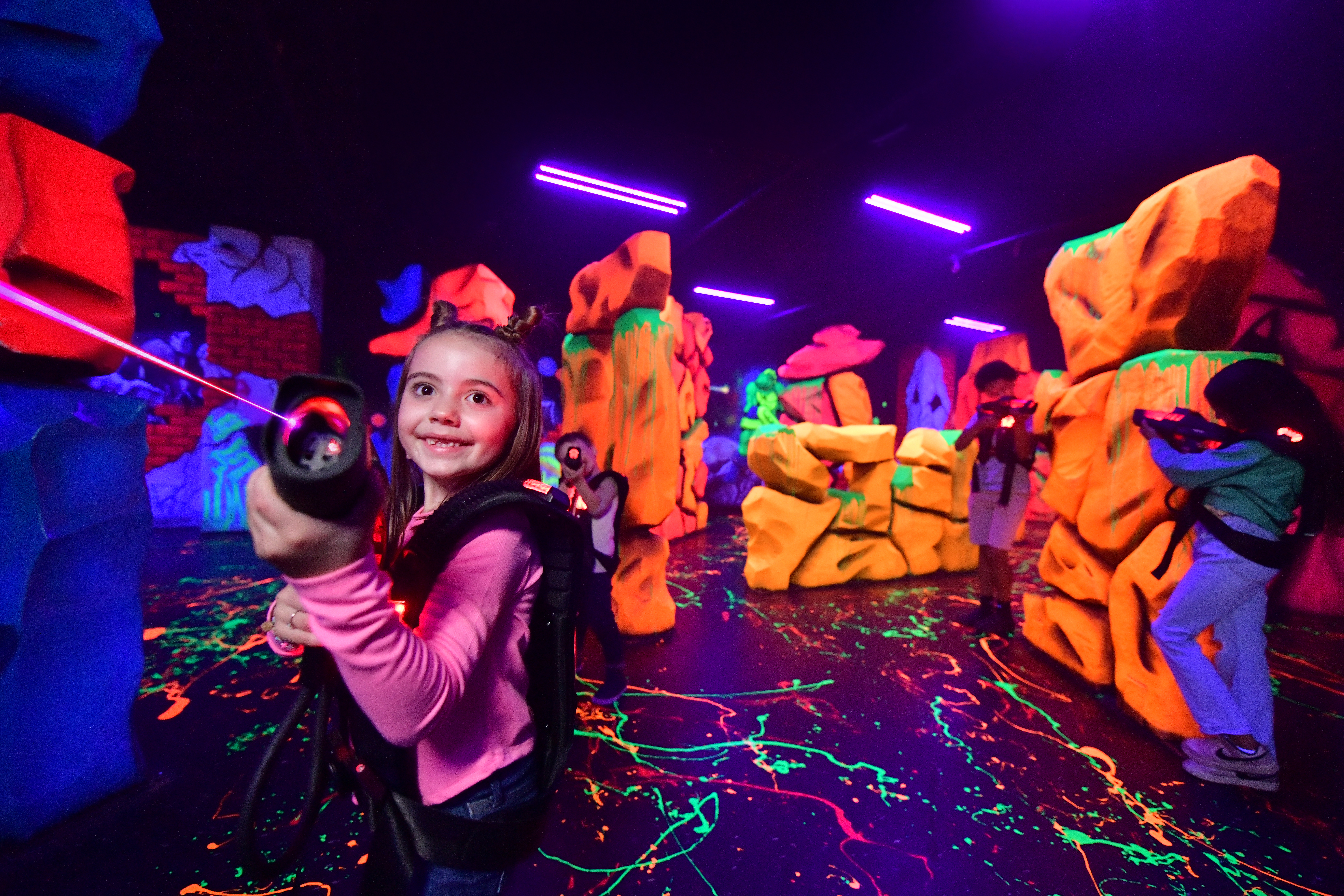 Girl shooting a laser gun with a bright neon background