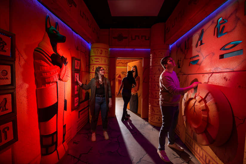 Three friends exploring the Wrath of Anubis Escape Room.