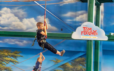 a little boy zip lining inside of tom foolerys adventure park