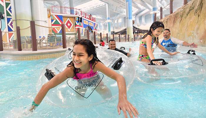 Girls smiling as they float down the lazy river in tubes