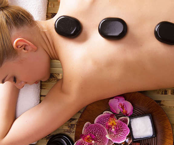 a woman laying on her stomach getting a hot stone massage in the spa