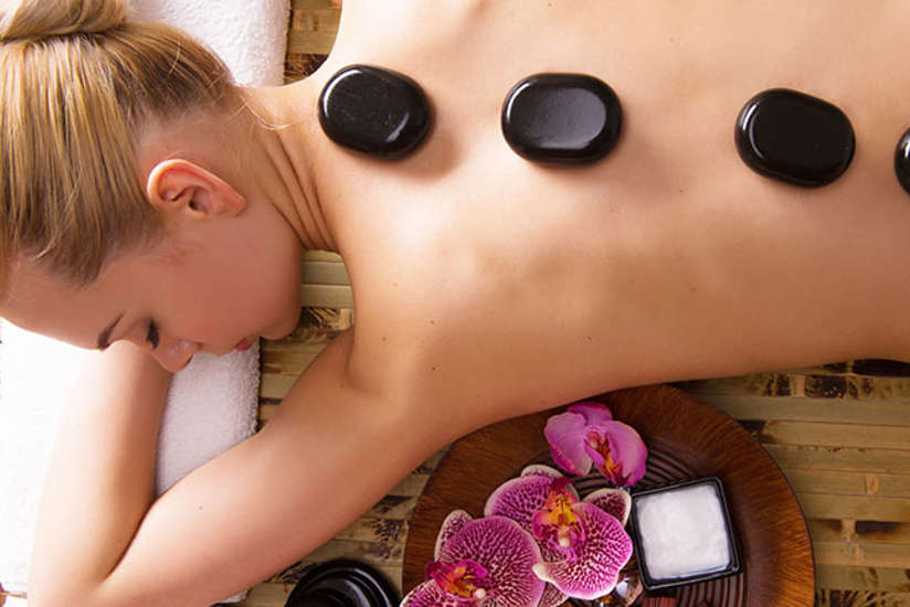 a woman laying on her stomach getting a hot stone massage in the spa