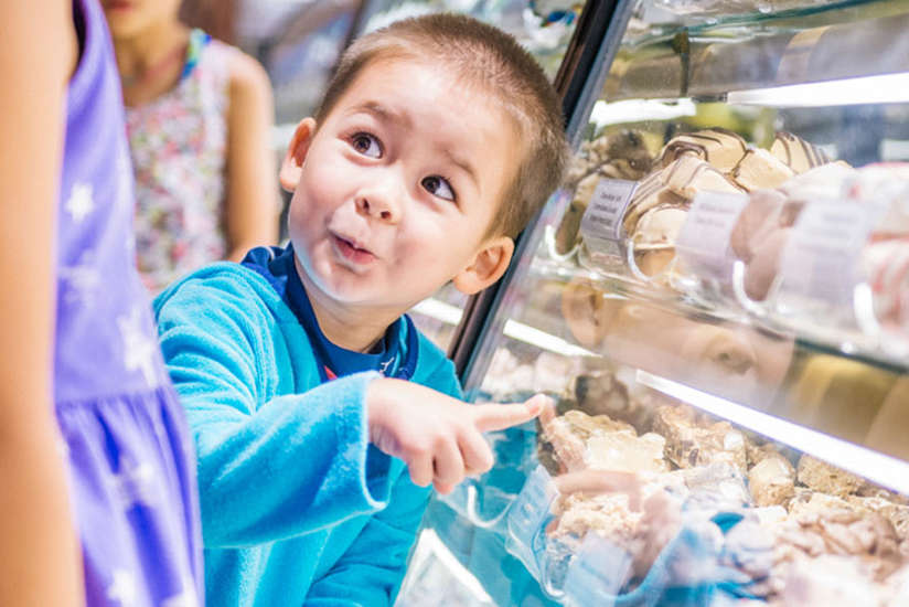 little boy pointing to some sweet treats in a bakery case