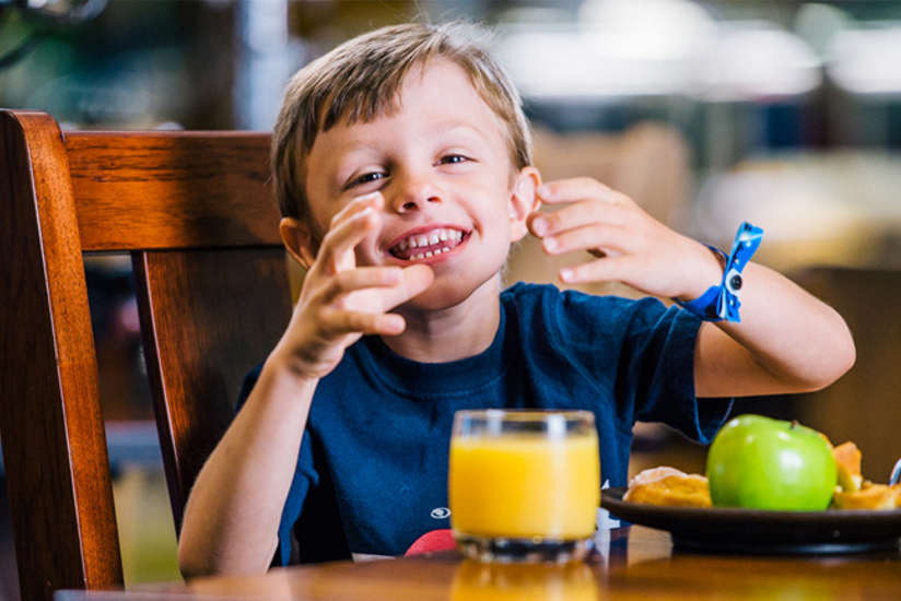 Little boy eating breakfast and smiling.
