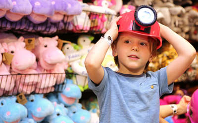 a boy with a hard hat on by a wall filled with stuffed animals