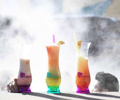 3 Monster Cocktail Drinks sitting on the side of a steaming outdoor whirlpool