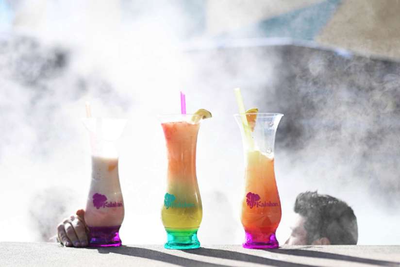 3 Monster Cocktail Drinks sitting on the side of a steaming outdoor whirlpool