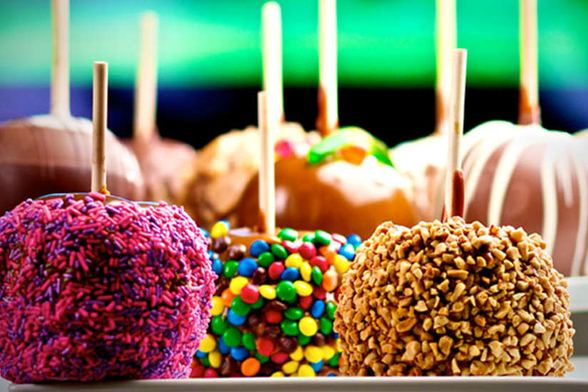 three caramel apples with different toppings
