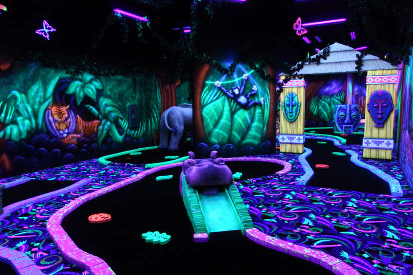 blacklight mini golf course with a glowing jungle and jungle animals