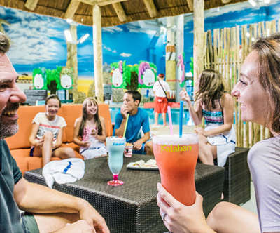 family enjoying themselves and some food and drinks inside a cabana.