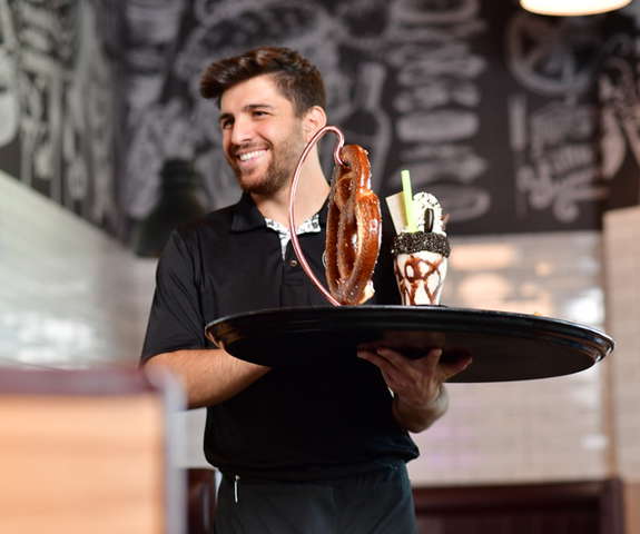Server delivering a hot pretzel and a milkshake